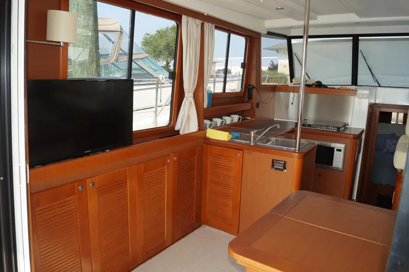 Slide: The Image of Interior of 2014 Beneteau Swift Trawler 34 with kitchen, TV, and wooden cabinetry. - 16