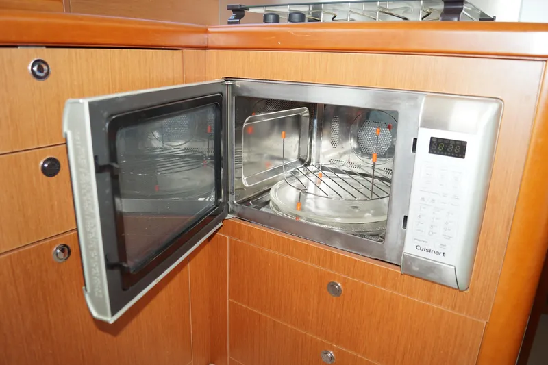 Slide: The Image of Microwave oven in 2014 Beneteau Swift Trawler 34 kitchen, with open door and wooden cabinetry. - 19