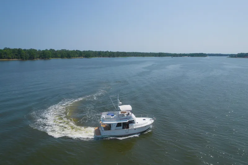 Slide: The Image of 2014 Beneteau Swift Trawler 34 cruising on a serene lake under clear skies. - 3