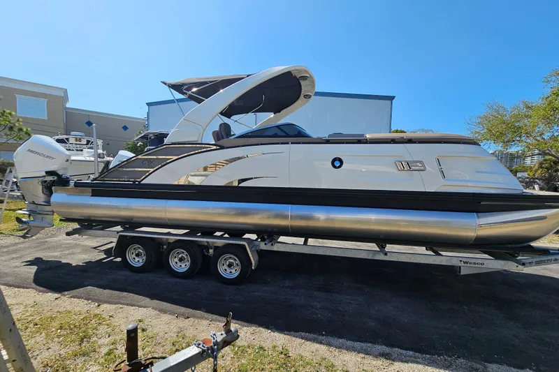 Slide: The Image of 2025 Bennington QX 27 QXSBWA X2 Swingback pontoon boat on trailer, sunny day. - 6