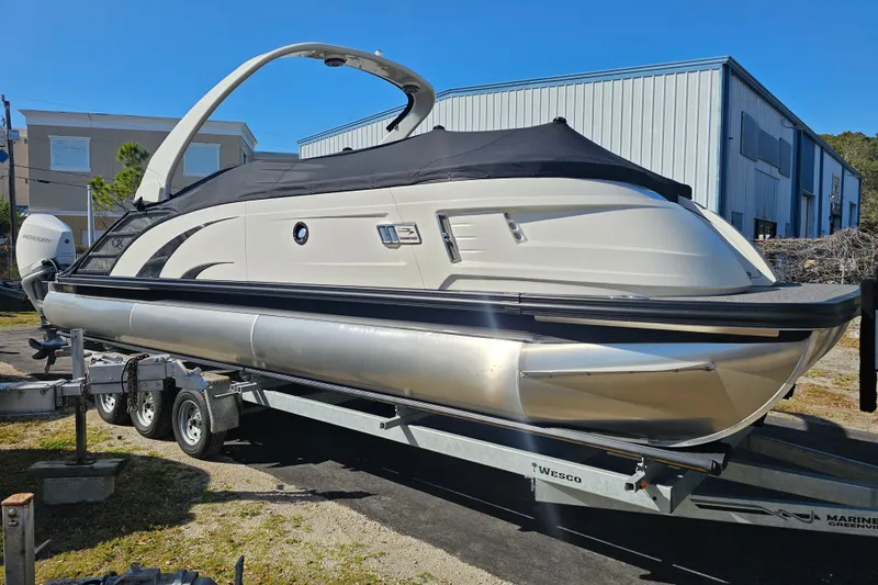 Slide: The Image of 2025 Bennington QX 27 QXSBWA X2 Swingback pontoon boat on trailer, covered and parked outdoors. - 9