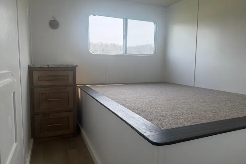 Slide: The Image of Interior of 2026 Sumerset Voyager with bed platform, window, and wooden drawers. - 8