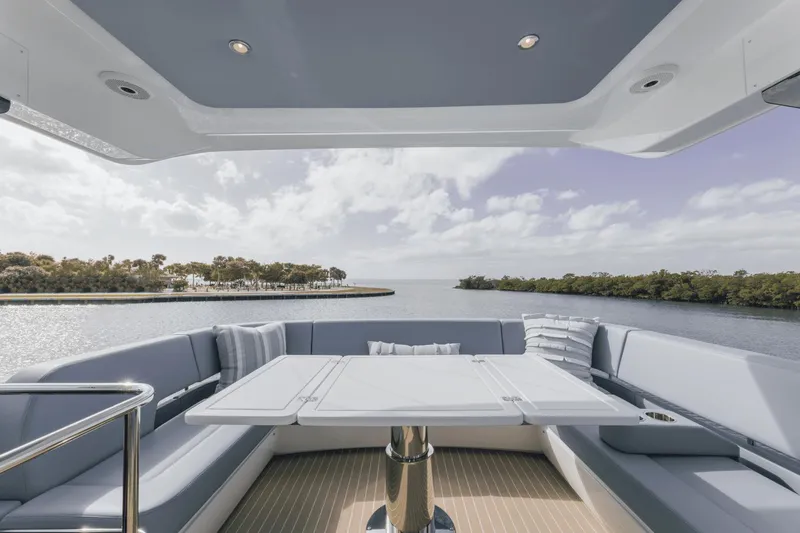 Slide: The Image of 2025 Cruisers Yachts 57 Fly, luxurious deck view with seating, overlooking serene waterway. - 22