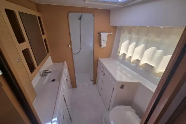 Slide: The Image of 2018 Lagoon 42 yacht bathroom with shower, sink, and toilet, featuring modern design and natural light. - 13