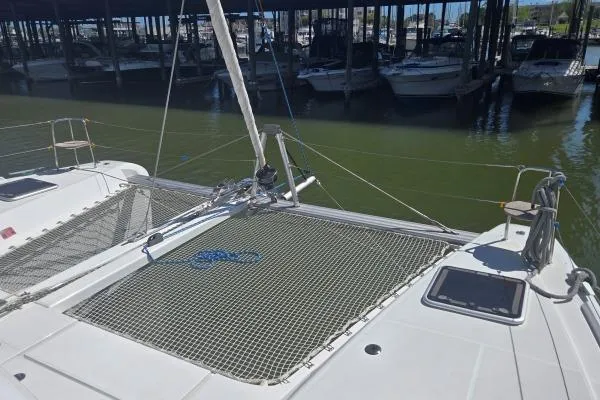 Slide: The Image of 2018 Lagoon 42 catamaran docked, featuring netted deck and marina backdrop. - 20