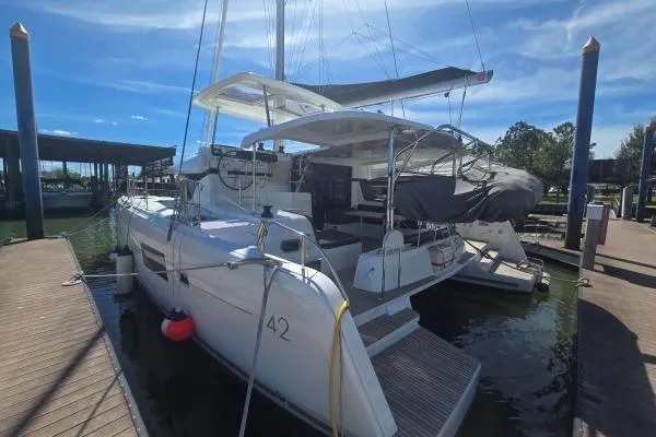 Slide: The Image of 2018 Lagoon 42 catamaran docked at marina under clear blue sky. - 23