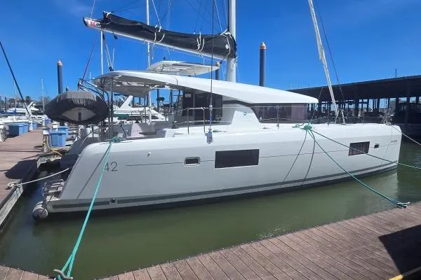 Slide: The Image of 2018 Lagoon 42 catamaran docked at marina under clear blue sky. - 24