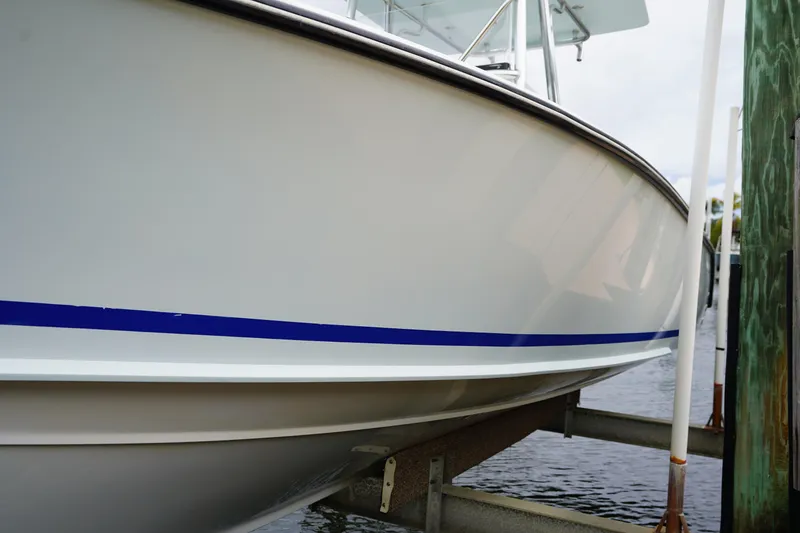 Slide: The Image of Stuart 26 boat from 2015 on a lift, featuring a sleek blue stripe. - 19