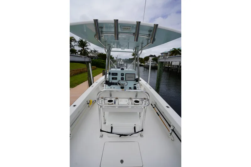 Slide: The Image of 2015 Stuart 26 boat interior with helm, controls, and seating, docked by a canal. - 37