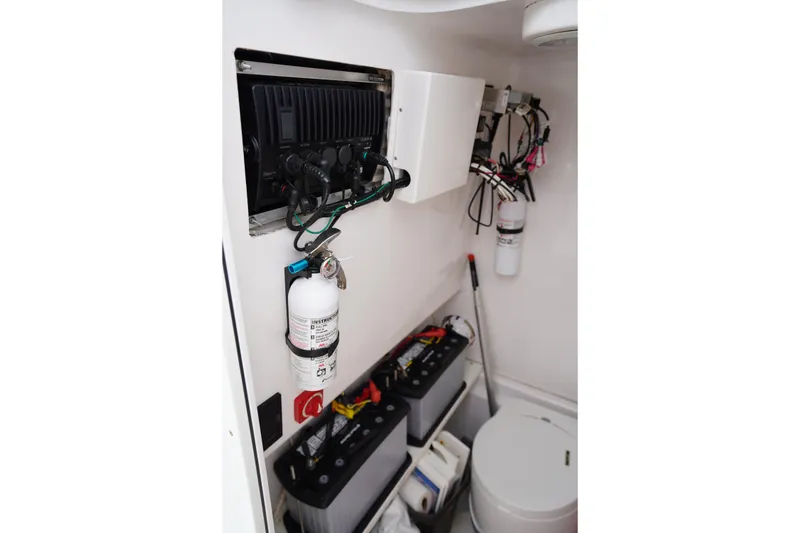 Slide: The Image of Electrical panel and equipment inside a 2015 Stuart 26 boat, featuring batteries and fire extinguisher. - 47