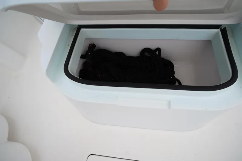 Slide: The Image of Open storage compartment on Stuart 26 boat, containing coiled black rope. - 52