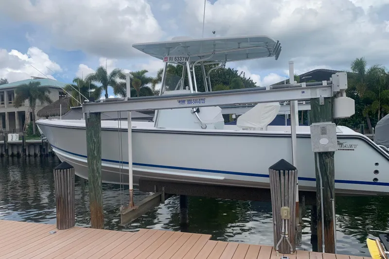 Slide: The Image of A 2015 Stuart 26 boat docked on a lift by a waterfront property. - 2