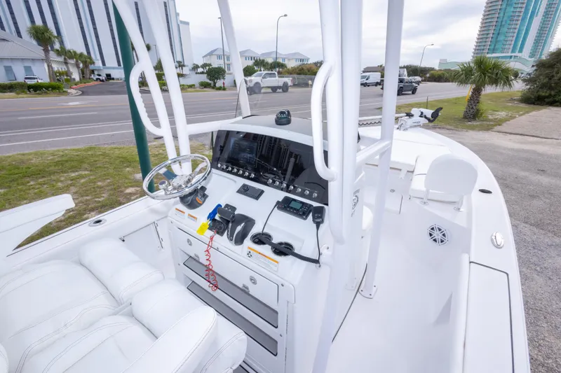 Slide: The Image of 2023 Sportsman Masters 227 Bay Boat dashboard with modern controls and seating, parked near a road. - 31
