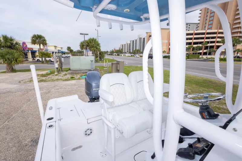 Slide: The Image of 2023 Sportsman Masters 227 Bay Boat with white seating and steering, parked near a road. - 41