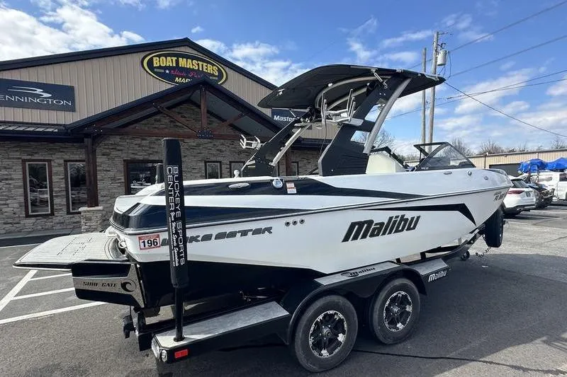Slide: The Image of 2018 Malibu Wakesetter 21 VLX boat on trailer at dealership, clear sky background. - 3