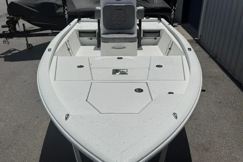 Slide: The Image of 2026 Avid 19 FSX boat with spacious deck and seating, parked outdoors. - 8