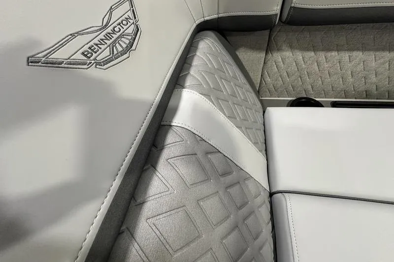 Slide: The Image of 2026 Bennington 24 M Quad Bench interior with embossed logo and textured upholstery. - 23