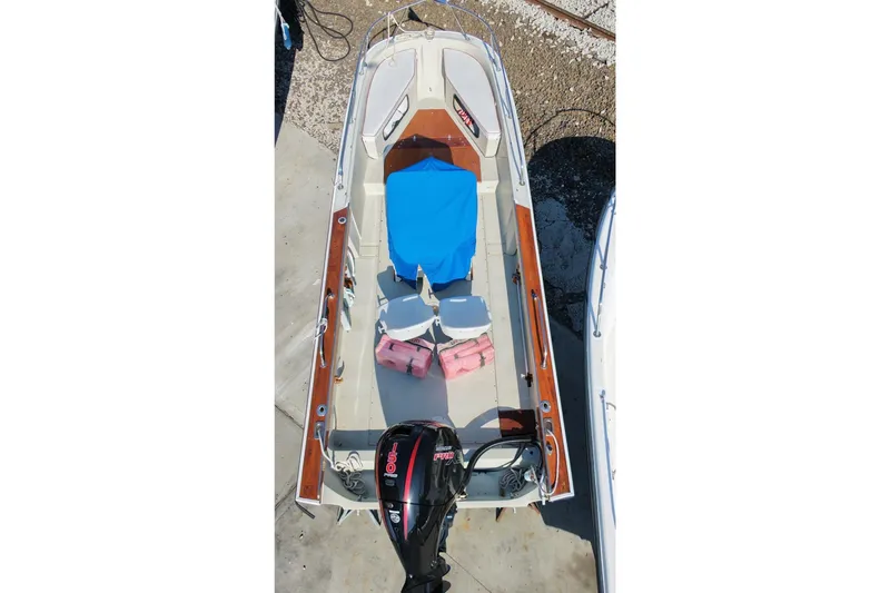 Slide: The Image of 1978 Boston Whaler Outrage 20 boat with blue cover and outboard motor, docked on concrete. - 10