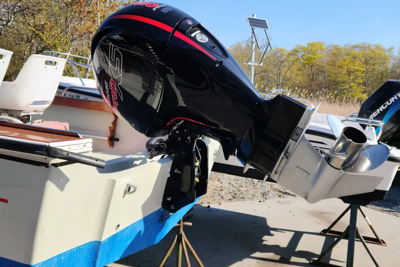 Slide: The Image of 1978 Boston Whaler Outrage 20 with powerful outboard motor, parked outdoors. - 24