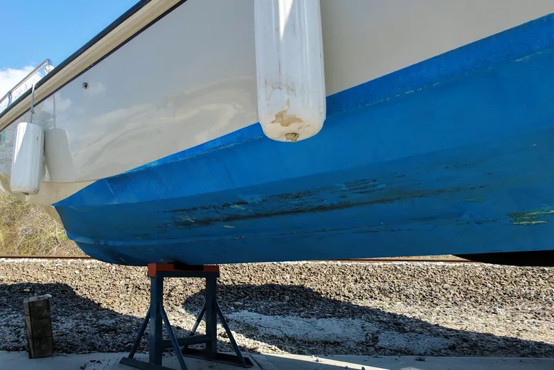 Slide: The Image of 1978 Boston Whaler Outrage 20 boat hull with blue paint, supported on stands. - 25