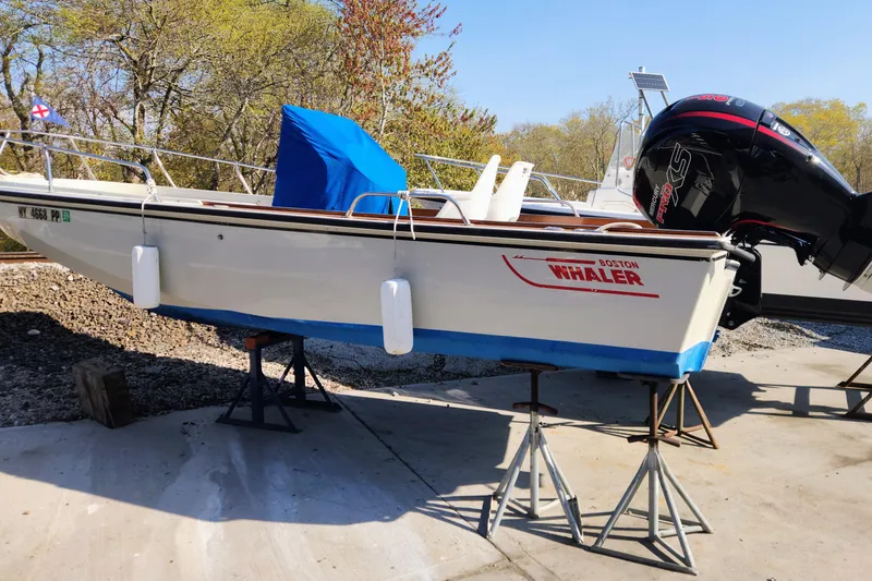 The Image of 1978 Boston Whaler Outrage 20 boat on stands, with blue cover and outboard motor. - 6