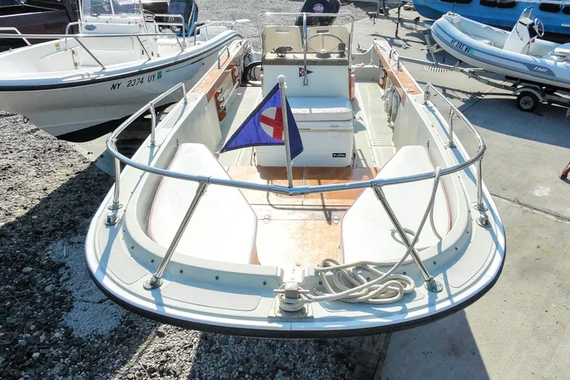 Slide: The Image of 1978 Boston Whaler Outrage 20 boat with flag, docked on concrete surface. - 8