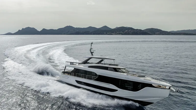 Slide: The Image of 2025 Azimut Grande 26M yacht cruising on open sea with scenic mountain backdrop. - 2