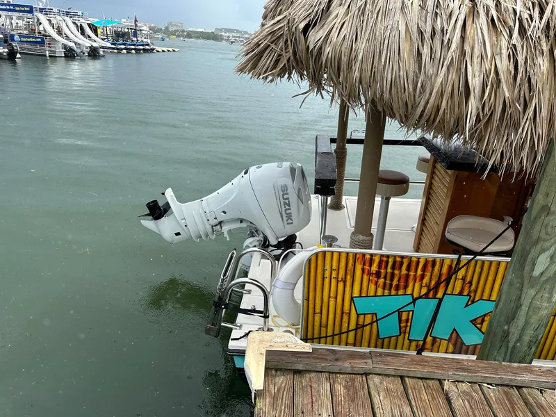 Slide: The Image of 2023 Beachcat 23 Catamaran with Suzuki outboard motor docked near tiki-themed bar. - 7