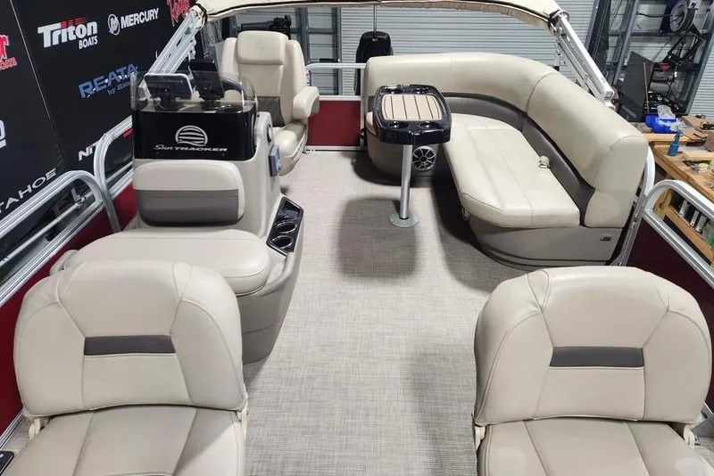 Slide: The Image of 2025 Sun Tracker Bass Buggy 16 XL Select pontoon boat interior with beige seating and table. - 2