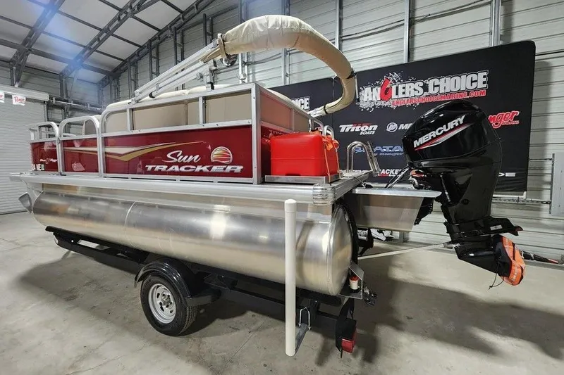 Slide: The Image of 2025 Sun Tracker Bass Buggy 16 XL Select pontoon boat with Mercury outboard motor in a showroom. - 7
