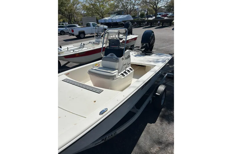 Slide: The Image of 2025 Mako Pro Skiff 13 CC boat in parking lot, featuring center console and outboard motor. - 2