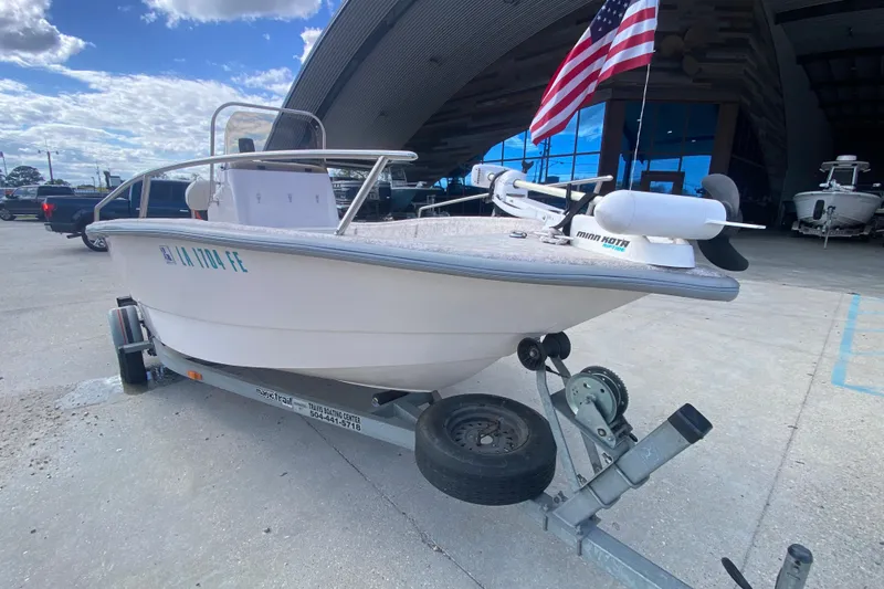 Slide: The Image of 2001 Fishmaster 17 boat on trailer with American flag, parked outside a building. - 10
