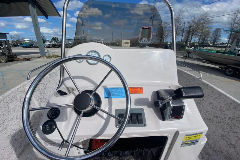 Slide: The Image of 2001 Fishmaster 17 boat console with steering wheel and controls, parked outdoors. - 13