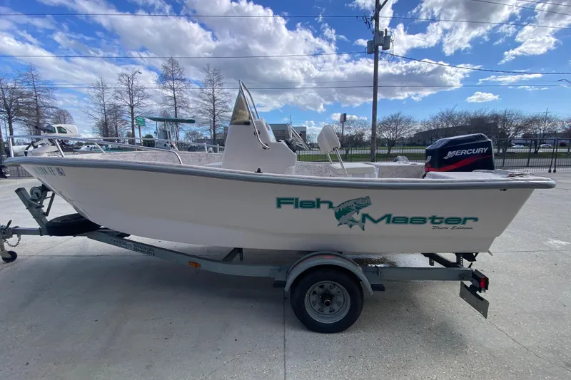 Slide: The Image of 2001 Fishmaster 17 boat on trailer with Mercury engine, parked outdoors under blue sky. - 7