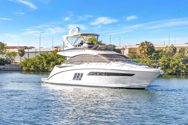 Slide: The Image of 2016 Sea Ray 510 Fly yacht cruising on a sunny day, surrounded by greenery. - 2