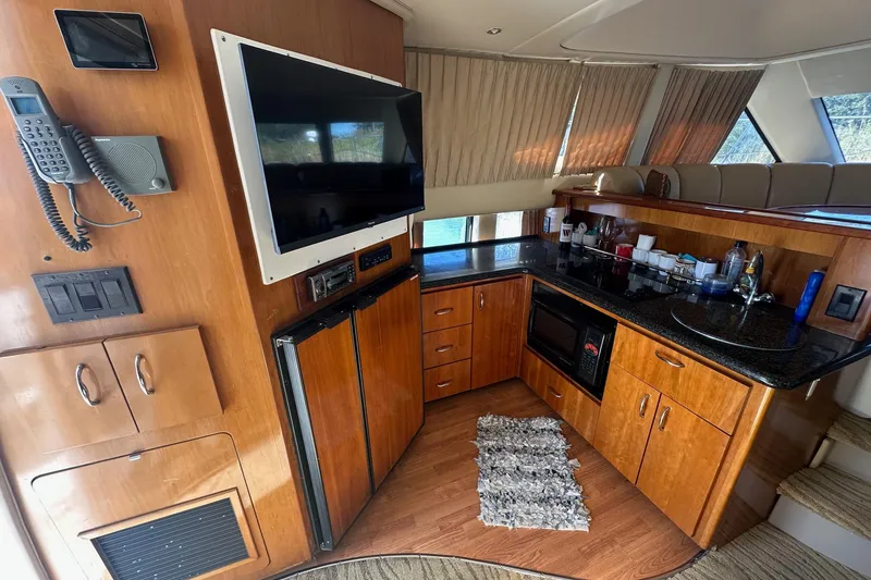 Slide: The Image of Interior of 2005 Carver 360 Sport Sedan with kitchen, TV, and wooden cabinetry. - 2