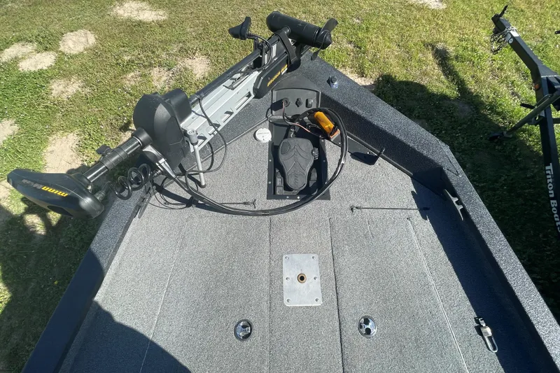 Slide: The Image of 2013 Xpress H18 boat deck with trolling motor and pedal controls on grass. - 1