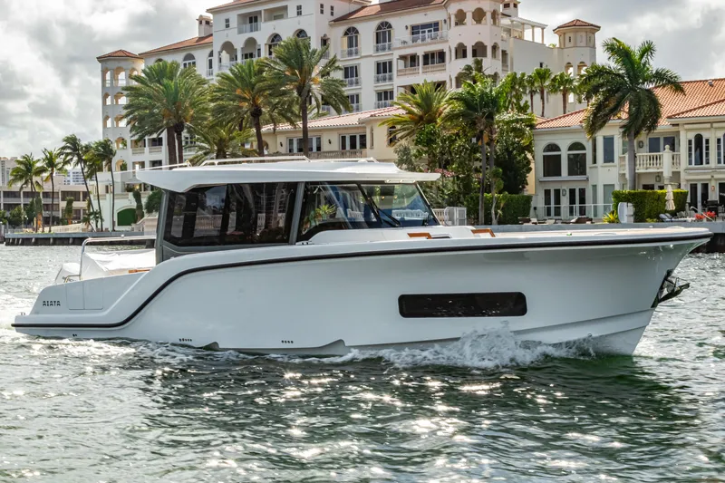 Slide: The Image of Aiata Wayfinder 38 Cabin 2026 cruising on water near luxury villas. - 24