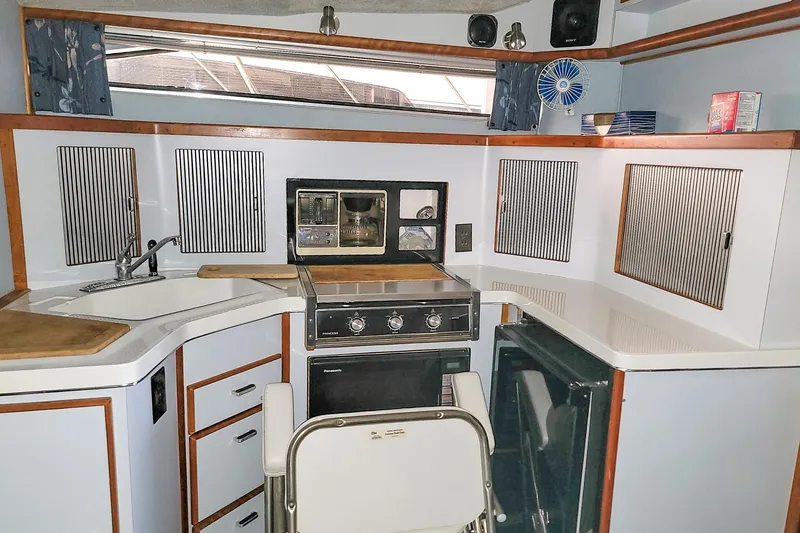 Slide: The Image of 1987 Sea Ray 340 Express Cruiser kitchen with stove, sink, and storage cabinets. - 14