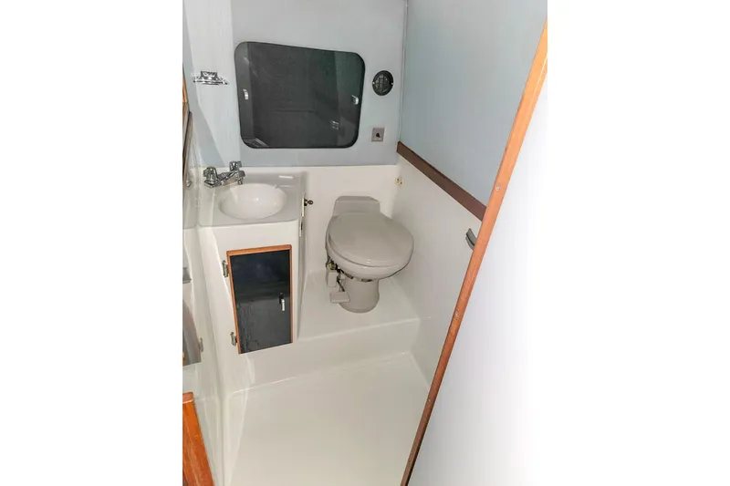 Slide: The Image of 1987 Sea Ray 340 Express Cruiser bathroom with sink, toilet, and storage cabinet. - 18