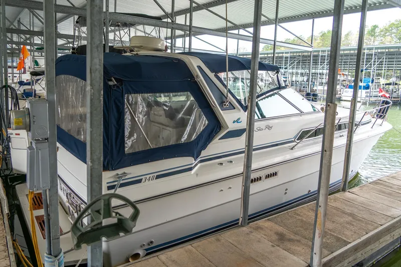 Slide: The Image of 1987 Sea Ray 340 Express Cruiser docked in a marina, covered with a blue canopy. - 3