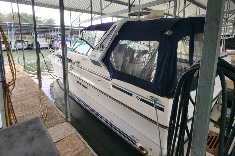 Slide: The Image of 1987 Sea Ray 340 Express Cruiser docked in a marina, covered with a blue canopy. - 5