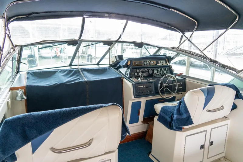 Slide: The Image of 1987 Sea Ray 340 Express Cruiser helm with blue and white seating, steering wheel, and controls. - 8