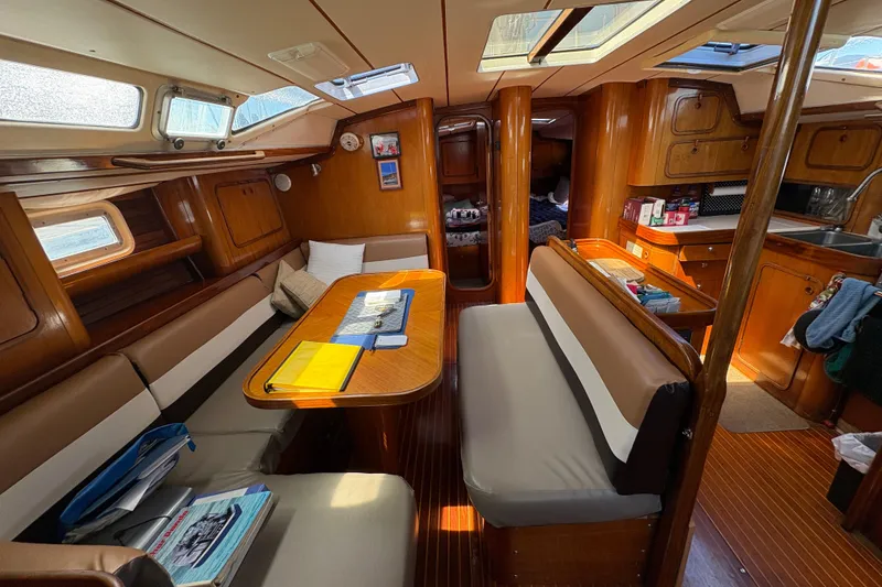 Slide: The Image of Interior of 1990 Beneteau Oceanis 500 sailboat, featuring cozy seating and wooden cabinetry. - 58