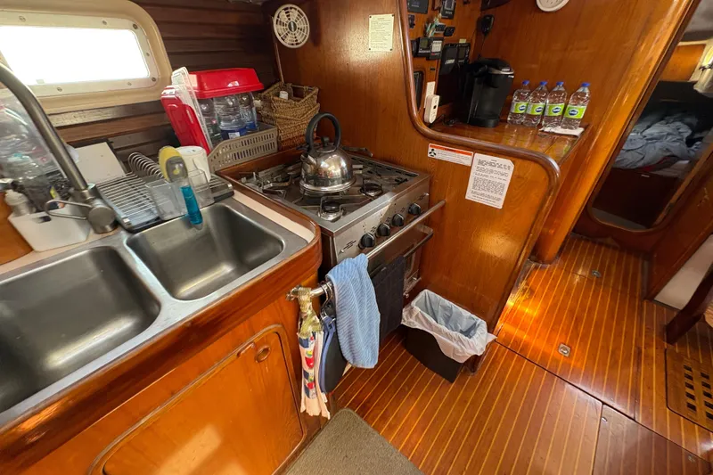 Slide: The Image of Galley kitchen in 1990 Beneteau Oceanis 500 sailboat with stove, sink, and wooden cabinetry. - 68