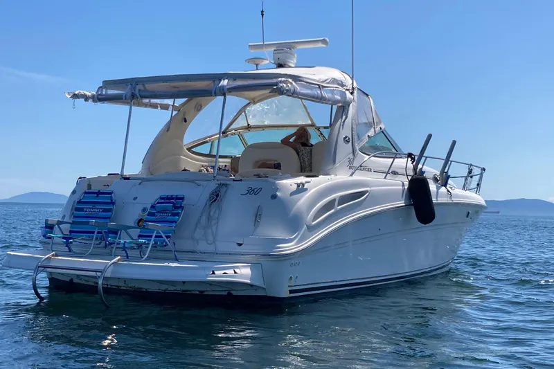 Slide: The Image of 2003 Sea Ray 360 Sundancer yacht on calm water, featuring a spacious deck and seating. - 71