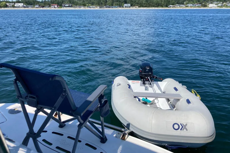 Slide: The Image of 2003 Sea Ray 360 Sundancer with inflatable dinghy on calm water, near shoreline. - 73