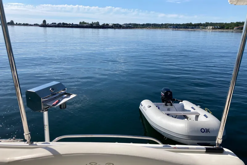 Slide: The Image of 2003 Sea Ray 360 Sundancer with grill and dinghy on calm water. - 75