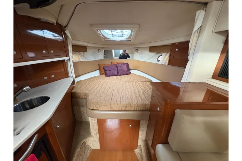 Slide: The Image of 2009 Sea Ray 290 Amberjack cabin interior with bed, sink, and wooden cabinetry. - 68