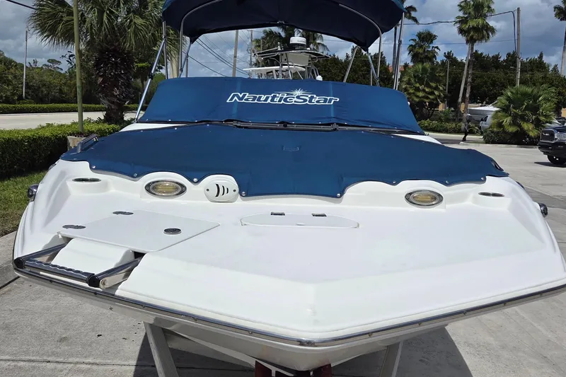 Slide: The Image of 2017 NauticStar 203DC Sport Deck boat with blue cover, parked outdoors. - 15
